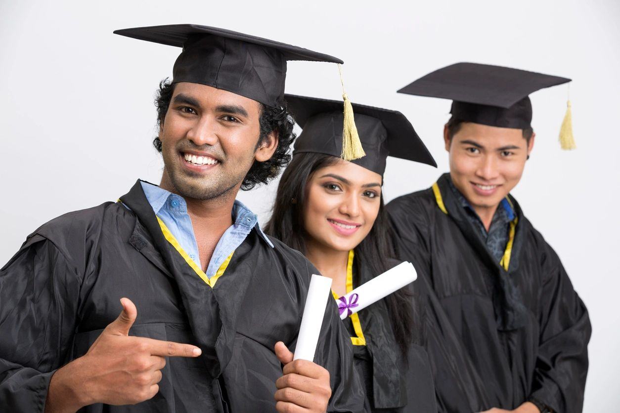 Three Olsen Academy graduates in caps and gowns holding diplomas